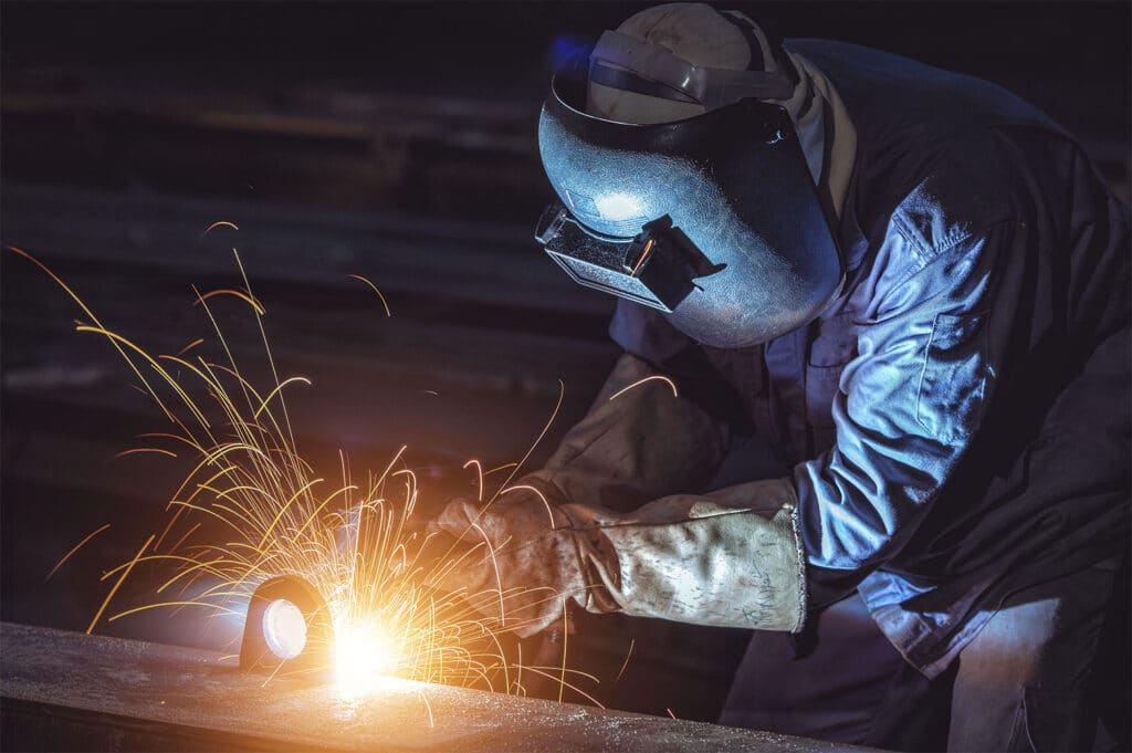 Man welding with protective clothing and face shield on